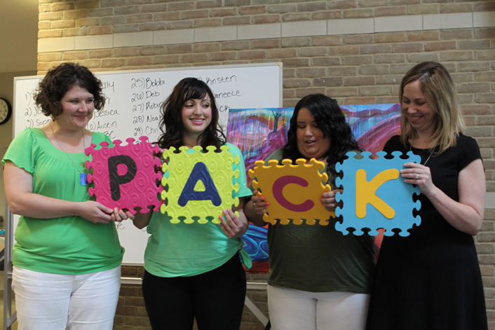 MA Synthesis- Group of Students holding foam letter puzzle pieces spelling out PACK