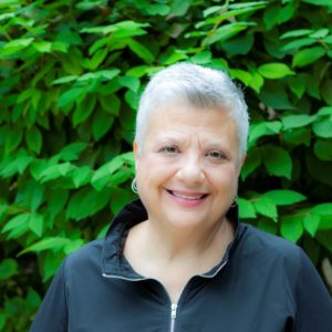 Photo of Dr. Fran Brown, PsyD in front of green plants.