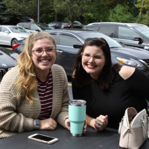 Two students posing at a table outside