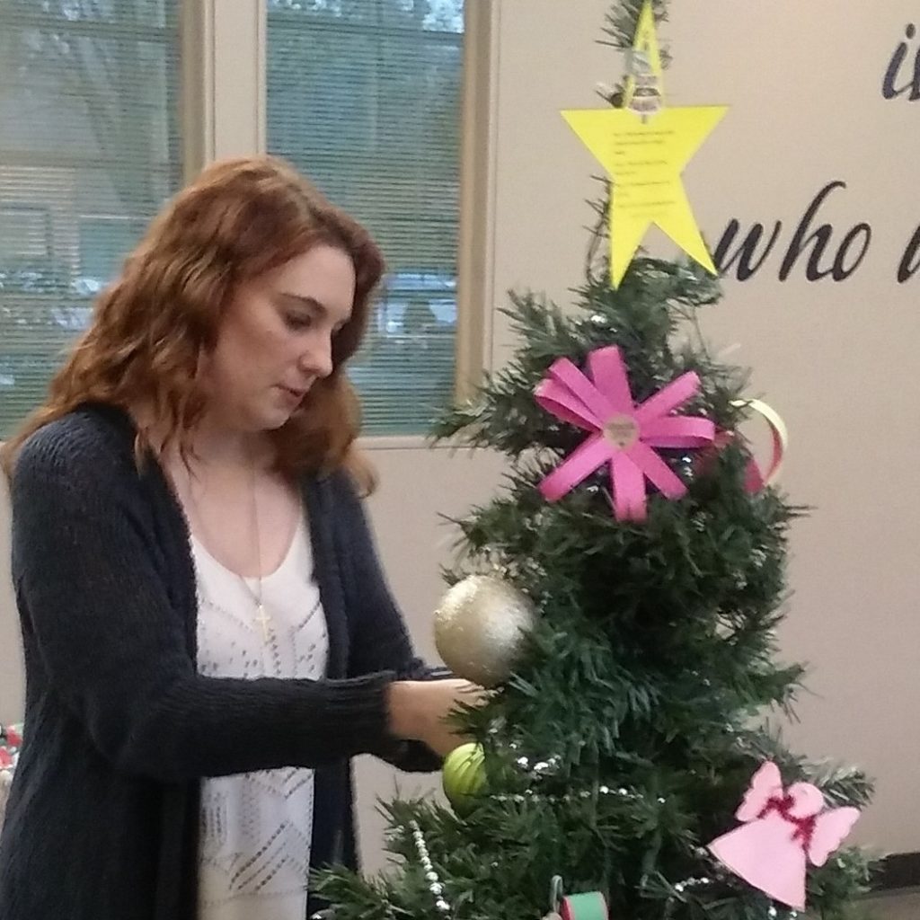 Photo of a student hanging ornaments on a Christmas tree