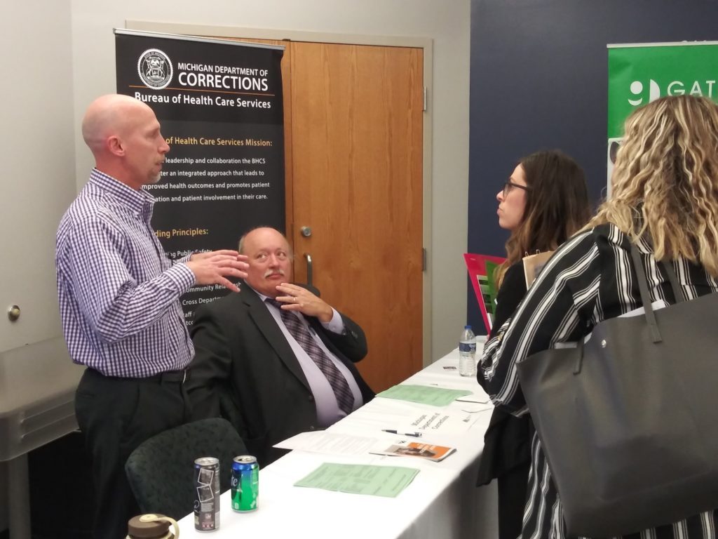 Photo of student talking to employers in front of a desk.