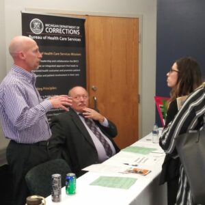 Photo of student talking to employers in front of a desk.