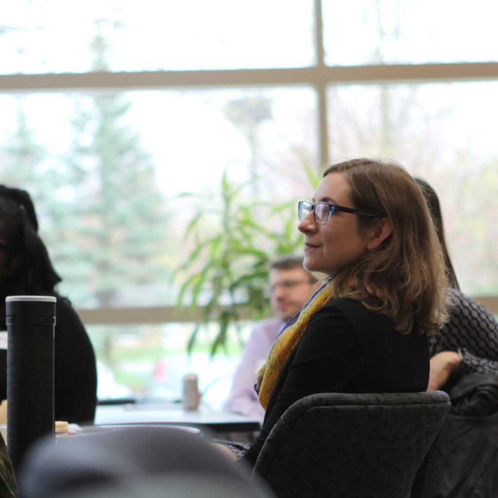 Photo of student sitting in the atrium listening to a presentation