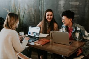 Photo of three people laughing at a table.