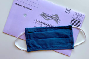 Photo of a mask laying on top of a ballot envelope.