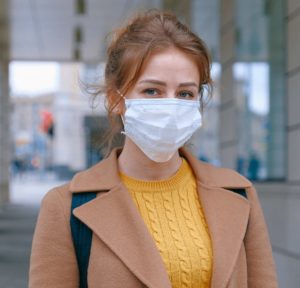 Photo of a woman wearing a backpack and a face mask.