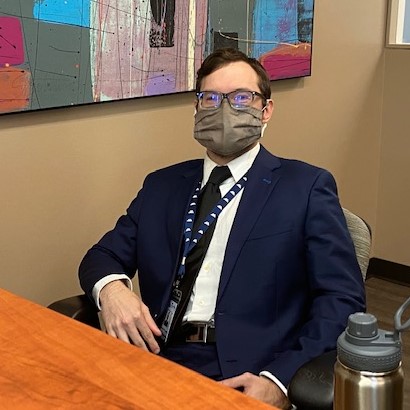 Photo of Kenneth McDermott wearing a mask and sitting at the front desk