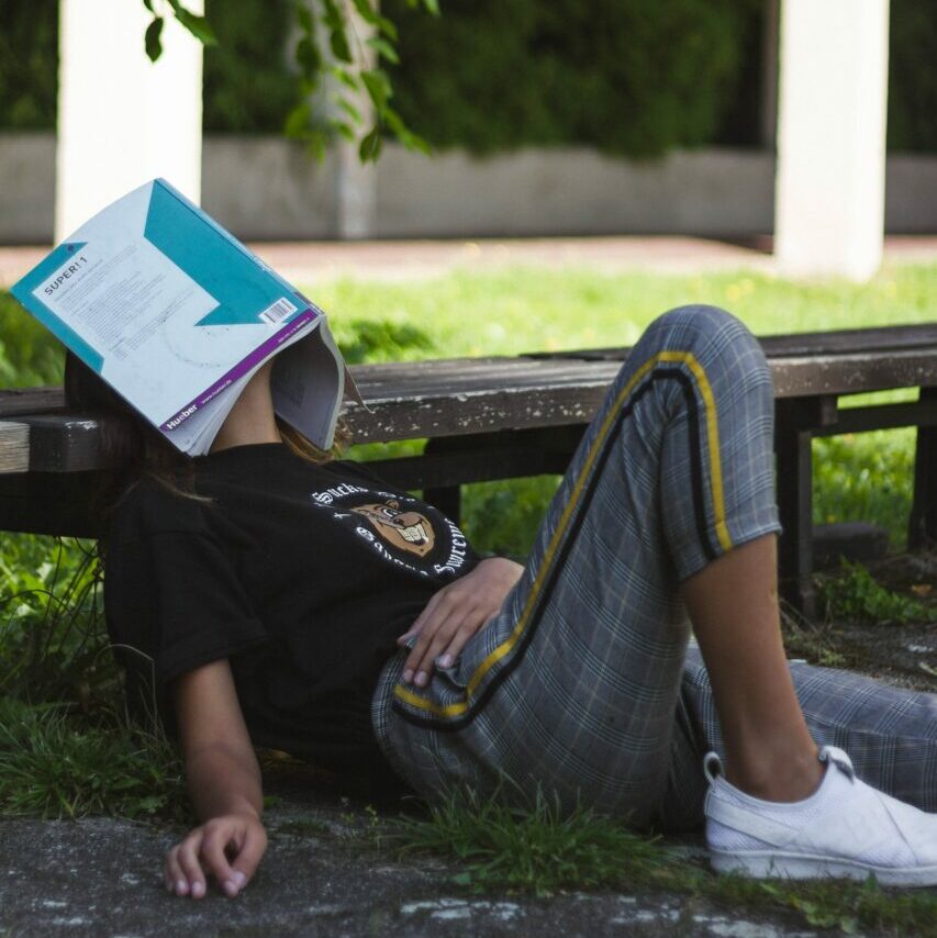 stock photo of a college age girl with a textbook over her face