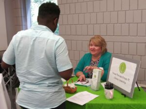 Student talking with representative at the Thrive Therapy Group table at the career fair