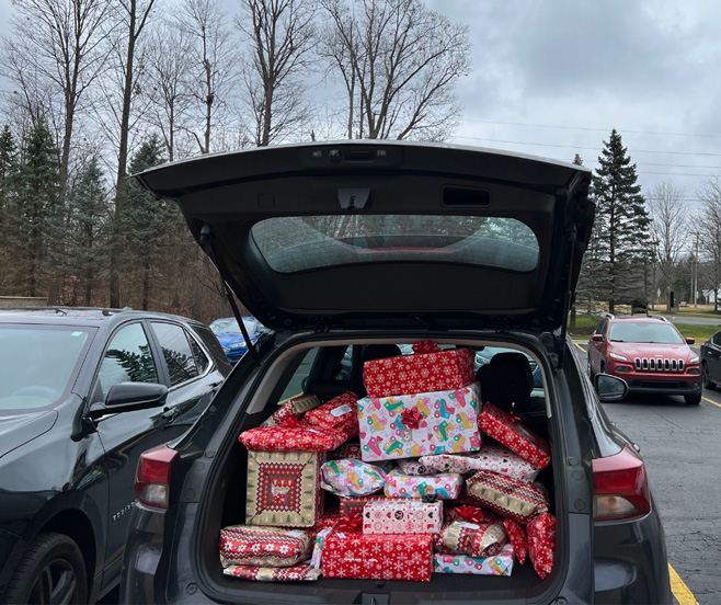 Photo of a hatchback with the trunk open to show a pile of wrapped gifts.