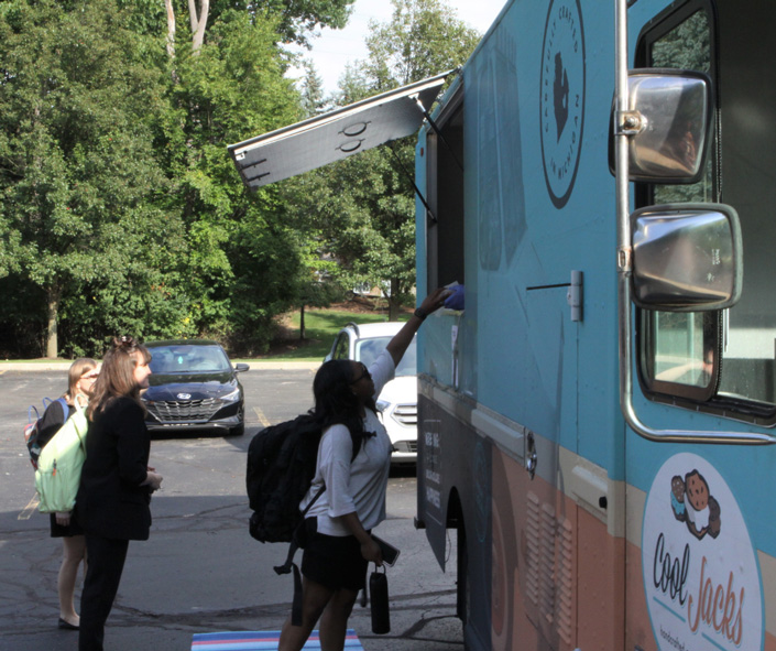 Student reaching up to Cool Jacks food truck window to receive their ice cream.