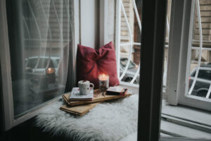 Stock photo of a cozy reading seat on a window with pillows and a lit candle. 