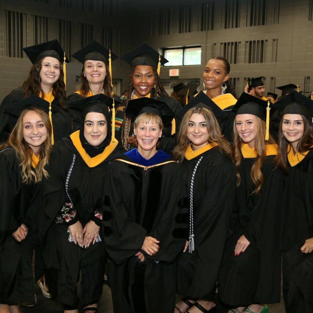 Group of ABA graduates in their regalia posing with Dr. Ruth Anan