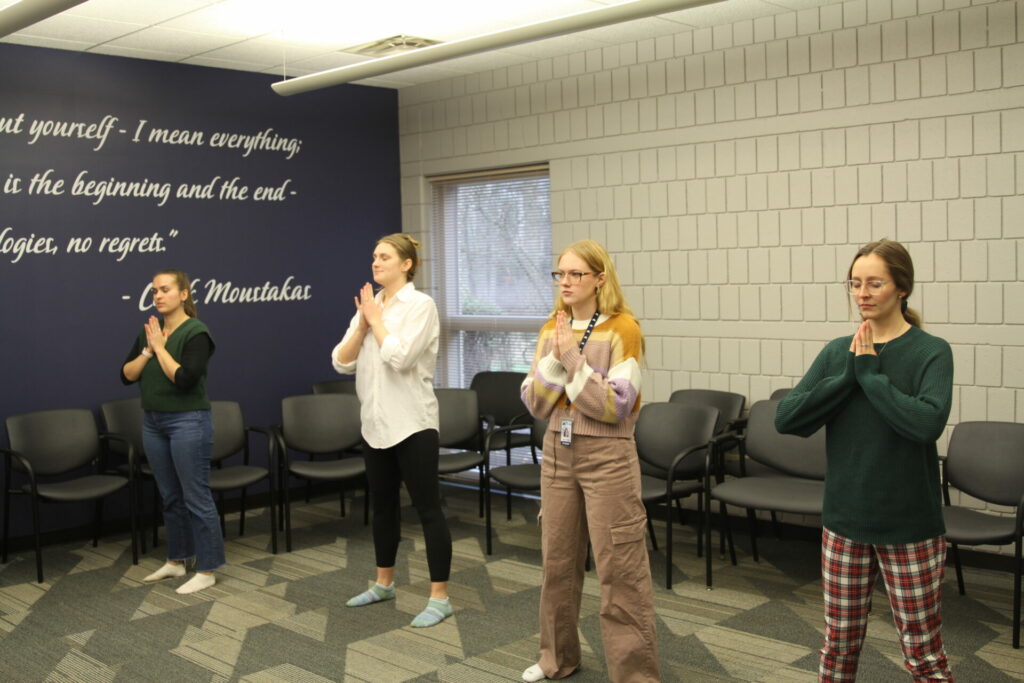 Four women practicing yoga in a classroom.